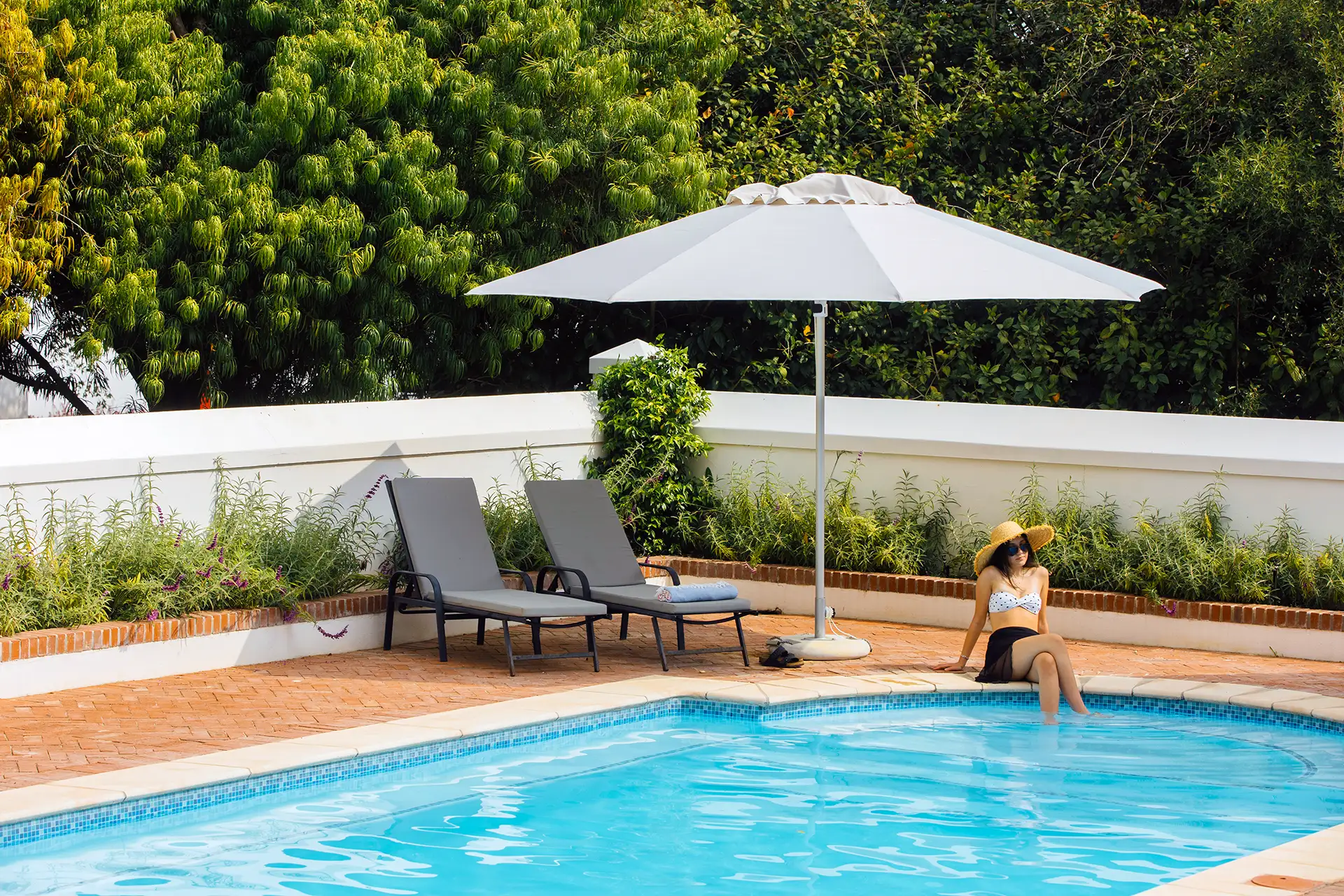 Woman by a pool under a Solara Living parasol